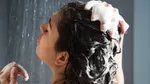 Žena koja šamponira kosu pod tušem